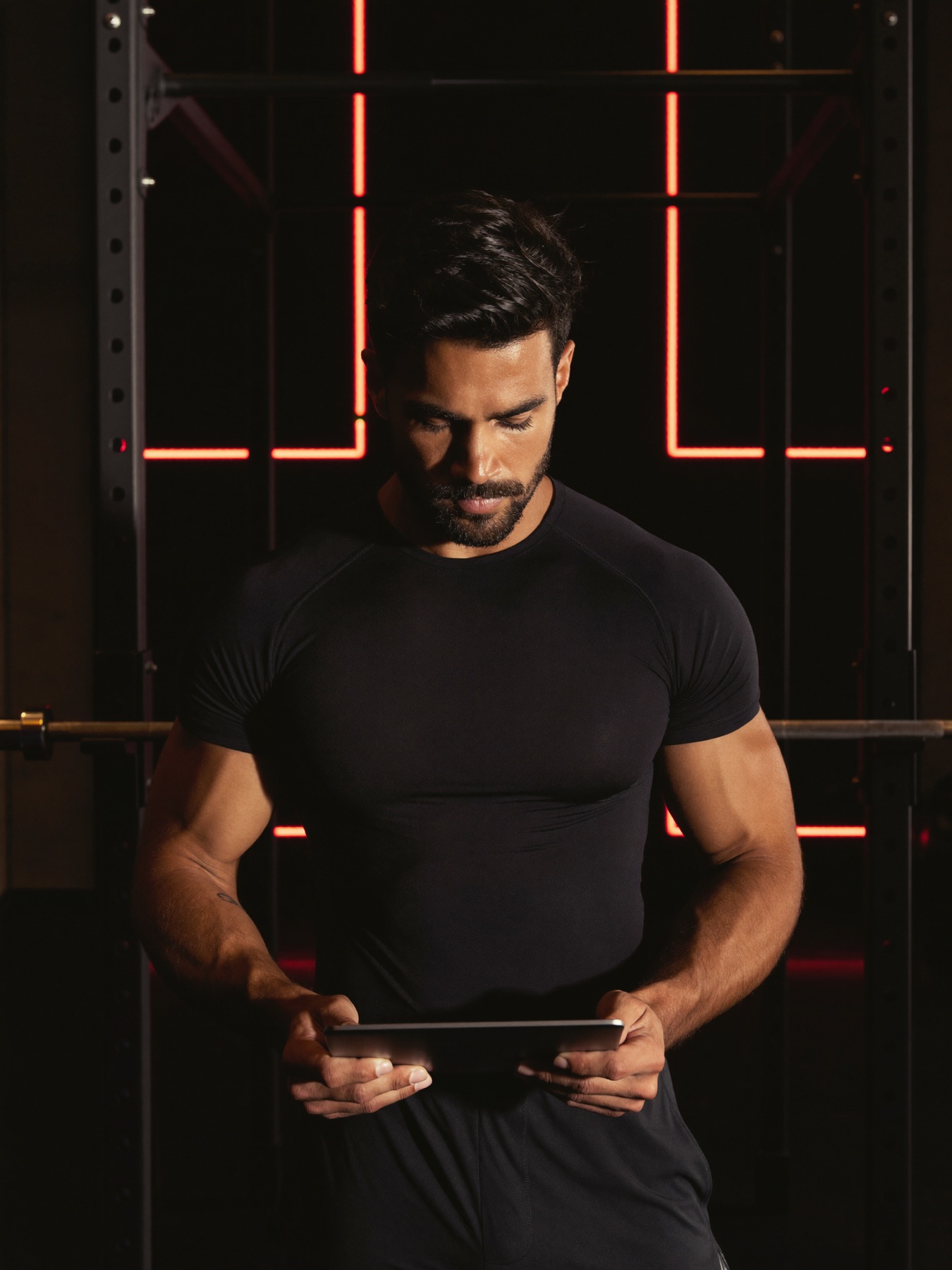 Trainer reviewing client sessions on a tablet in a dark gym